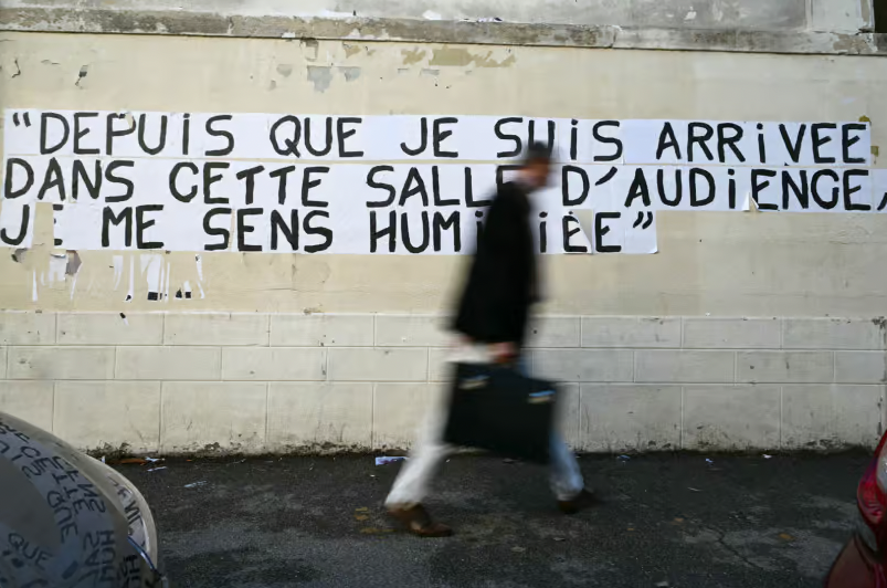 Un homme passe devant un collage d'une phrase prononcée par Gisele Pelicot au procès de Mazan, à Avignon, le 10 octobre 2024. © Christophe SIMON / AFP